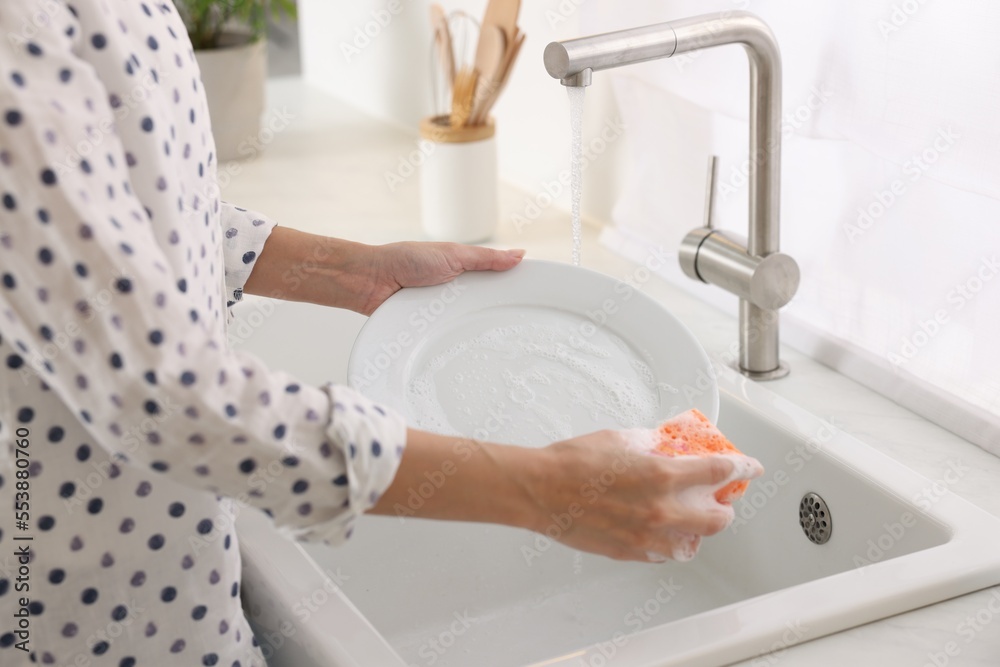 Woman washing plate above sink in modern kitchen, closeup Woman washing plate above sink in modern kitchen, closeup