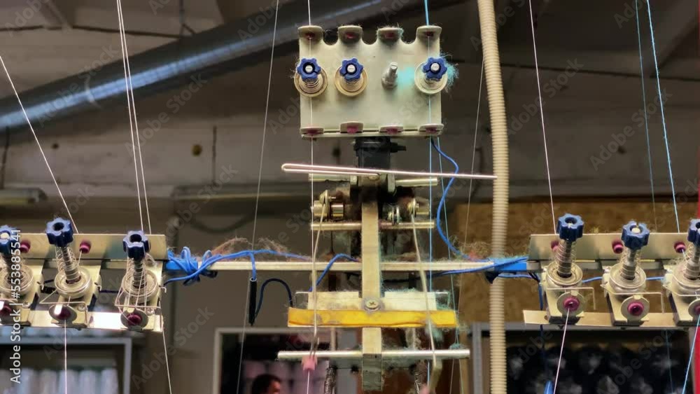 Robotic machine pulls threads while sewing clothes or fabric production, front view, close up. Process of operation of the equipment in a small sewing factory.