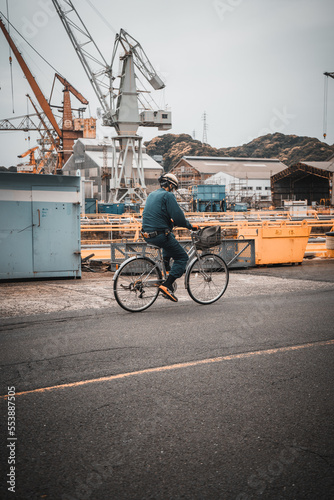 Man riding his bicycle to work wearing a hardhat - Japanese - Japan, Sasebo 