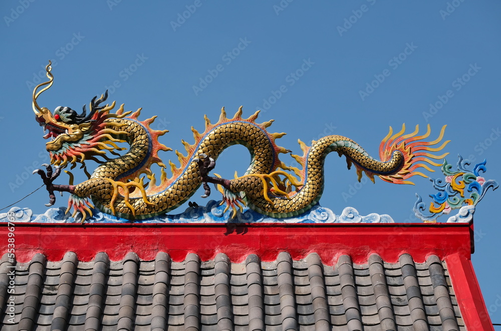 Dragon on roof of Chinesse shrine against blue sky Dragon on roof of Chinesse shrine against blue sky