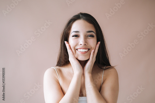Beauty portrait of young asian woman with healthy dark long hair in top on beige background