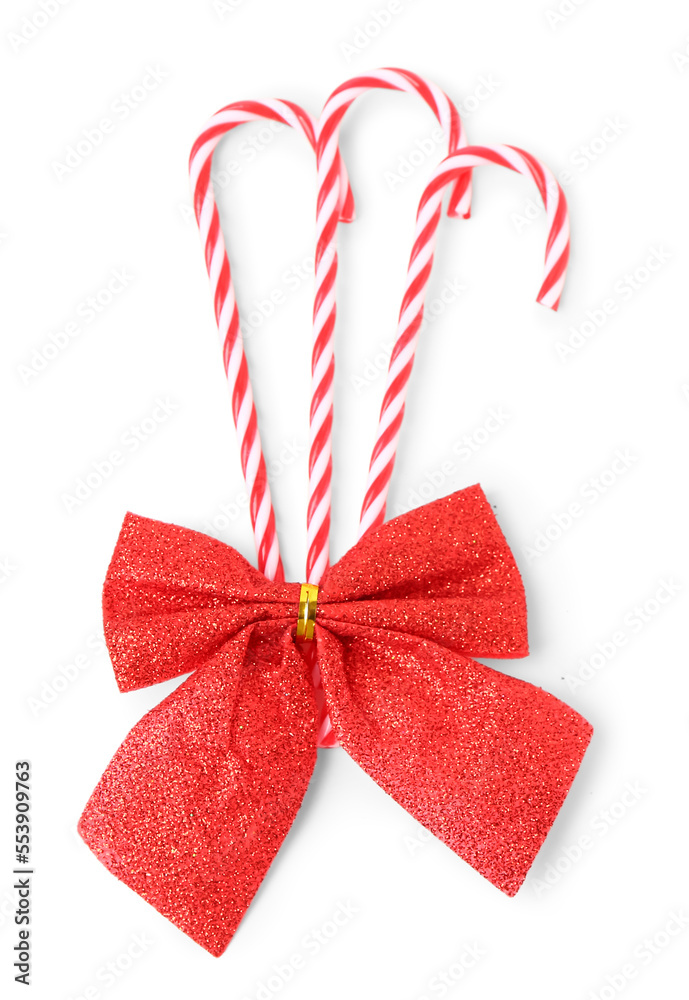 Sweet candy canes and Christmas bow on white background Sweet candy canes and Christmas bow on white background
