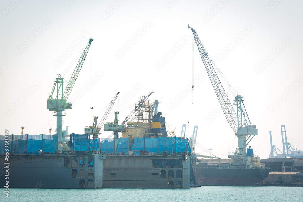 A crane is lifting loads in a shipyard.
