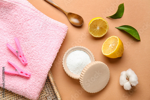 Laundry detergent, towels and lemon on beige background
