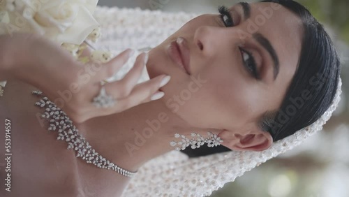 young woman in a wedding dress and jewelry posing at the camera. vertical video