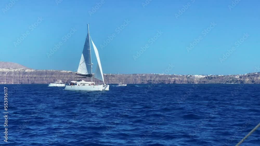 Luxury Catamaran Yacht And Boats Sailing At The Seascape Of Santorini Island, Greece. Aerial Wide Shot Luxury Catamaran Yacht And Boats Sailing At The Seascape Of Santorini Island, Greece. Aerial Wide Shot