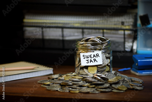 Glass Swear Jar overflowing Australian coins office setting  background copy space