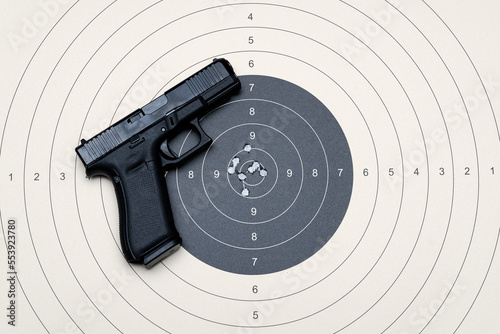 A compact 9mm pistol with a plastic frame and a target for shooting with bullet holes in the center.