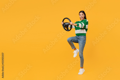 Full body side profile view happy young latin woman wear casual cozy green knitted sweater hold steering wheel driving car isolated on plain yellow background studio portrait People lifestyle concept.