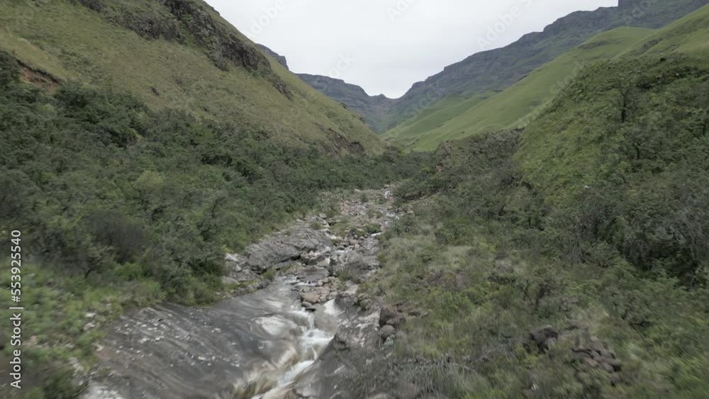 Aerial: Water erosion has cut small river through rugged green valley Aerial: Water erosion has cut small river through rugged green valley