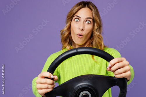 Schilderij op canvas Young cheerful shocked woman 30s wearing casual green knitted sweater hold steering wheel driving car look camera isolated on plain pastel purple background studio portrait