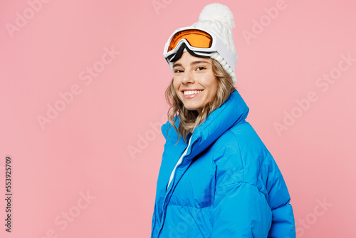 Sise view happy snowboarder woman wear blue suit goggles mask hat ski padded jacket spend extreme weekend look camera isolated on plain pastel pink background. Winter sport hobby trip relax concept.