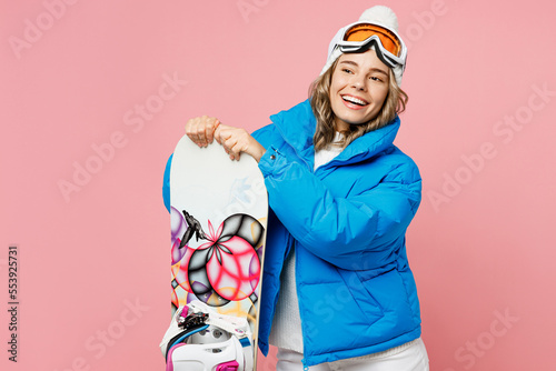 Snowboarder woman in blue suit goggles mask hat ski padded jacket look aside on workspace area mock up isolated on plain pastel pink background Winter extreme sport hobby weekend trip relax concept