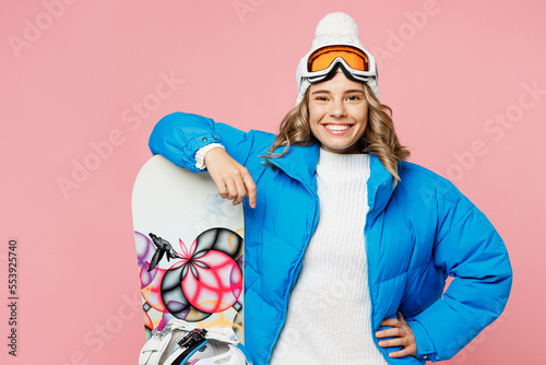 Snowboarder smiling happy cheerful woman wear blue suit goggles mask hat ski padded jacket stand akimbo isolated on plain pastel pink background. Winter extreme sport hobby weekend trip relax concept.