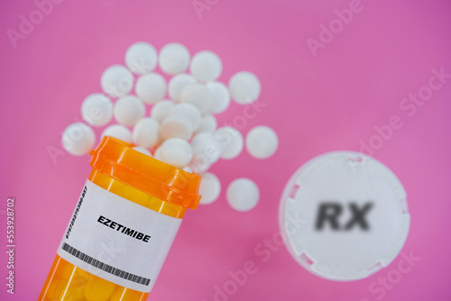 Ezetimibe Rx medicine pills in plactic vial with tablets. Pills spilling   from yellow container on pink background. photo