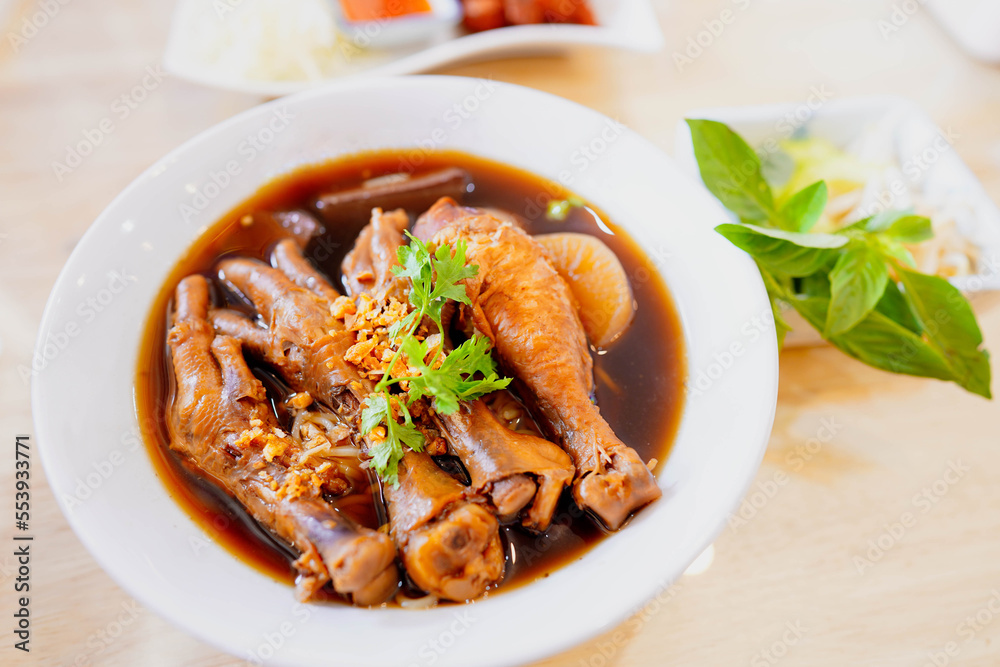 Braised chicken noodles or braised chicken leg in white bowl on table in restaurant, Thai street food, tasty food of Thailand. Braised chicken noodles or braised chicken leg in white bowl on table in restaurant, Thai street food, tasty food of Thailand.
