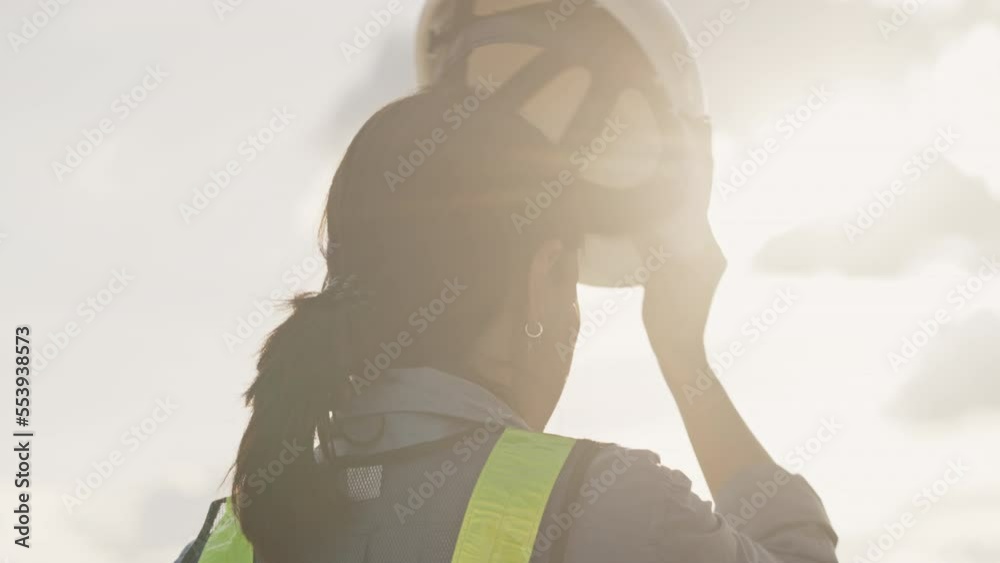 Slow motion of a female engineer putting a construction helmet on at sunset,Work and engineering Concept,Long hair,Close-up