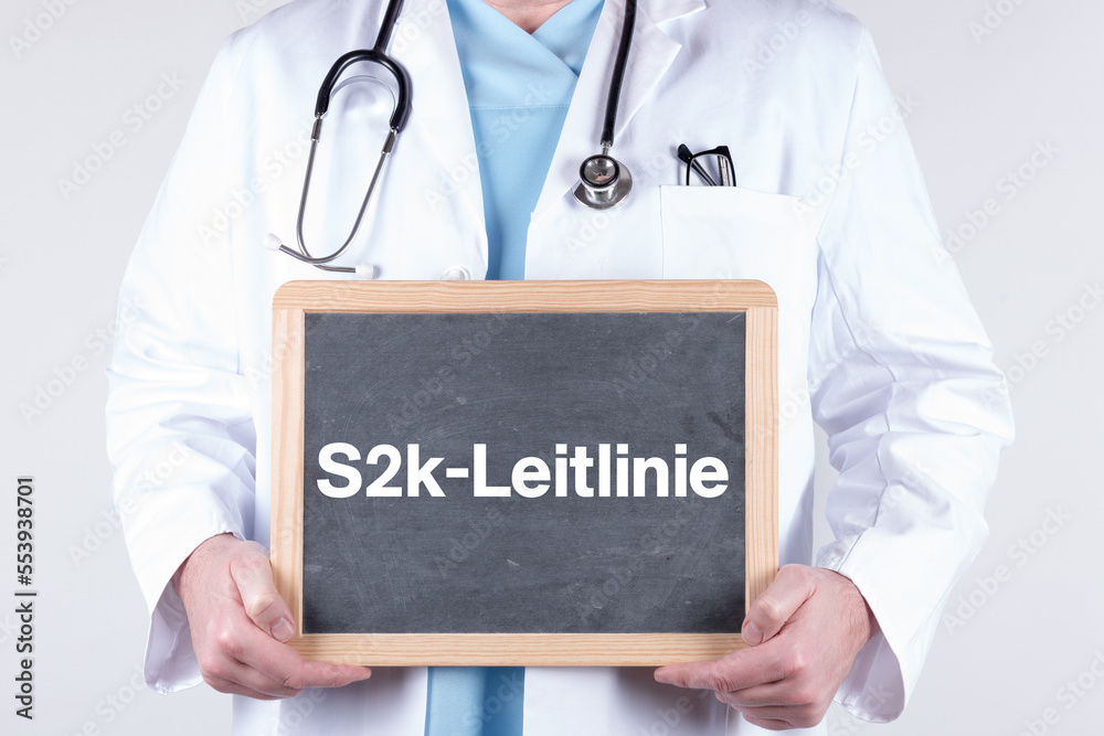 Arzt mit einer Tafel auf der S2K Leitlinie steht Arzt mit einer Tafel auf der S2K Leitlinie steht