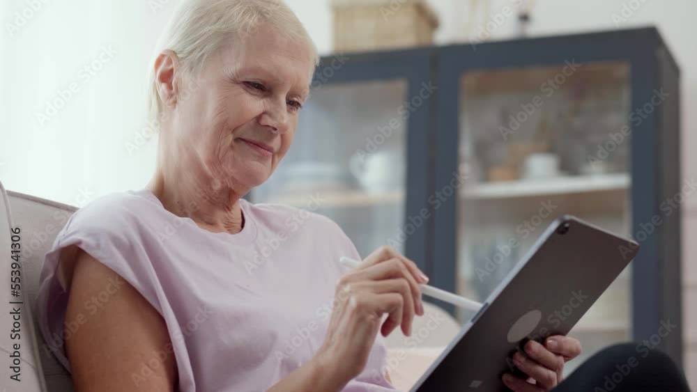attractive elderly woman reading an e-book in her living room. attractive elderly woman reading an e-book in her living room.