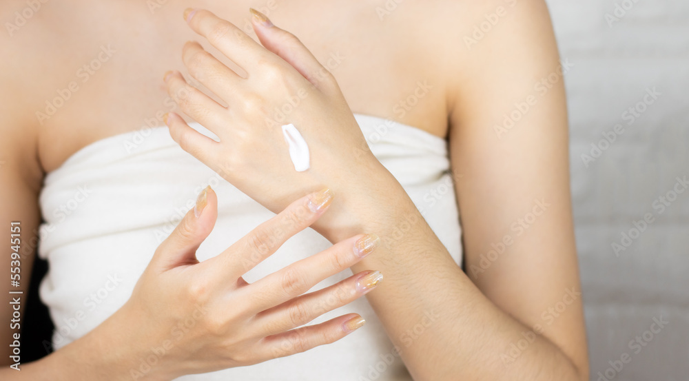 Fototapeta premium Beauty and spa treatment concept. Asian woman applying cream on hand.
