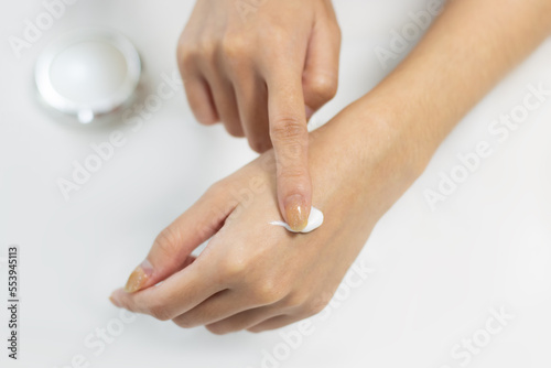 Woman applying cream on clean hand skin for beauty and spa treatment skin care on white color background. © CREATIVE WONDER