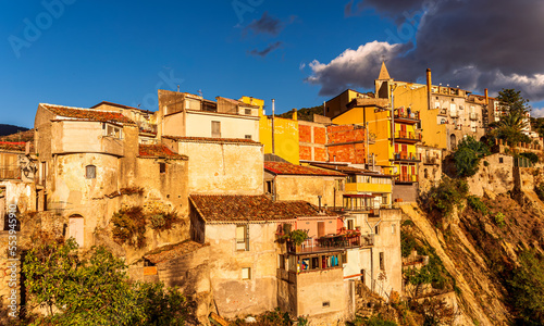 old mediterranean mountain dense town with levels of yellow houses and terraces on a mountain in evening light, vintage european village on a rock © Yaroslav