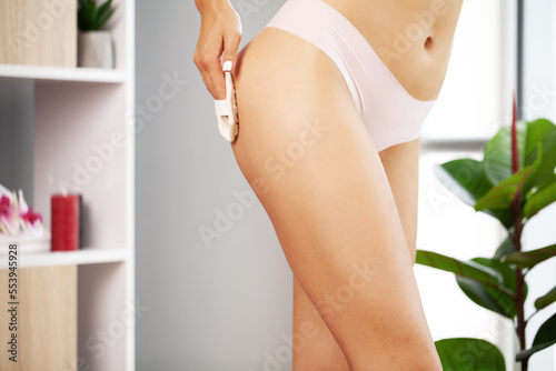 Woman making anti cellulite or lymphatic thigh massage at home