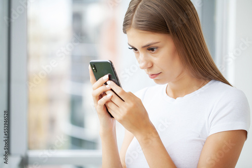 Attractive woman looking at smartphone screen, reading media news © Maksymiv Iurii