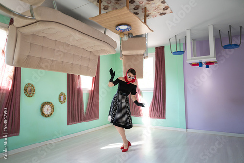 a girl retro style, surprised, in an upside-down house, as well as furniture placed on the up. photo