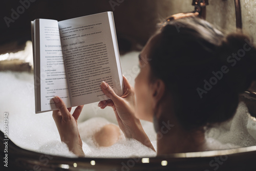 beautiful sexy girl in a bubble bath reading a book.