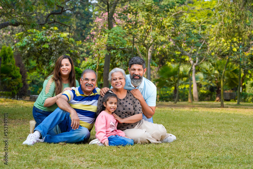 Happy indian or asian family sitting at park.