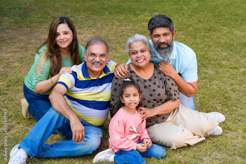 Happy indian or asian family sitting at park.