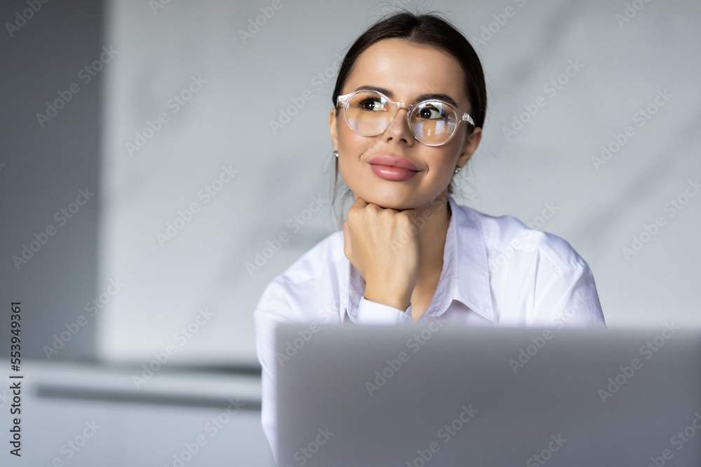 Portrait of a pretty young woman studying while sitting at the table with laptop at home Portrait of a pretty young woman studying while sitting at the table with laptop at home