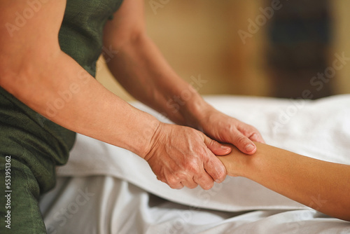 Hands of masseur pressing hands of patient in close up shot with warm tones photo