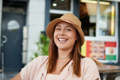 A beautiful Hispanic female smiling and sitting in a cafe on a sunny day