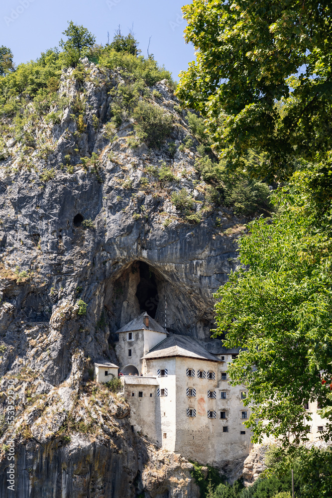 Built in Gothic and then rebuilt in Renaissance style Predjama Castle (Predjamski grad) under mountain shelter hidden by murky rocky stones, surrounded by green deciduous forest. Postojna, Slovenia