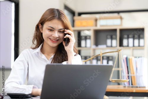 woman and lawyers discussing contract papers with brass scale on wooden desk in office.