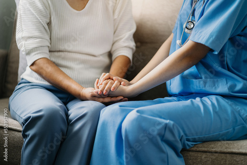 Friendly female doctor hands holding patient hand sitting at the desk for encouragement, empathy, cheering and support while medical examination.