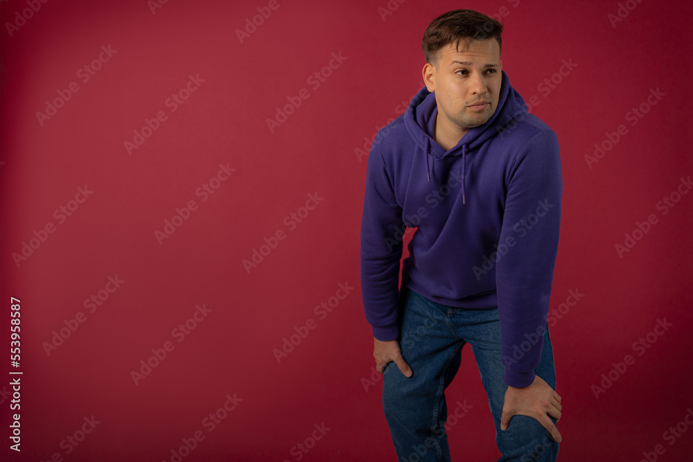 Attractive young man in a purple sweatshirt on a red background Attractive young man in a purple sweatshirt on a red background