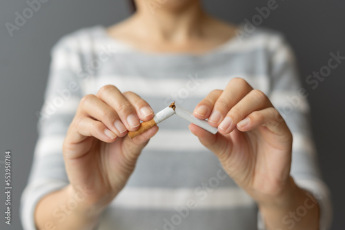 Portrait young woman holding broken cigarette in hands. Happy female quitting refusing smoking cigarettes. Quit bad habit  Stop smoking cigarettes  health care concept. No smoking campaign.