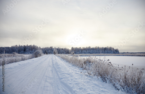 Winter landscape with snowy road and forest covered with hoar frost  selective focus