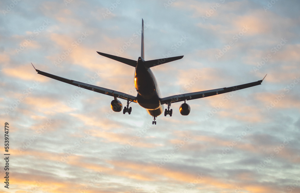 The silhouette of a passenger plane coming in for landing against the backdrop of the sunset sky. The silhouette of a passenger plane coming in for landing against the backdrop of the sunset sky.