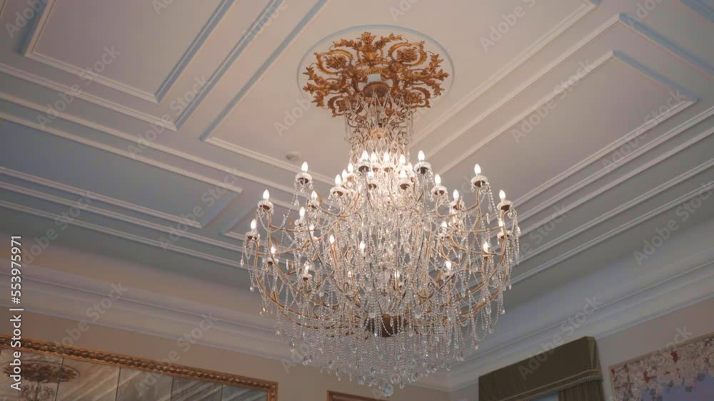 Rich Victorian style chandelier hanging on ceiling ornate with gold, many lightbulb illuminating room, crystal pendants decorating vintage chandelier. Retro hanging lamp in palace hall, museum room or Rich Victorian style chandelier hanging on ceiling ornate with gold, many lightbulb illuminating room, crystal pendants decorating vintage chandelier. Retro hanging lamp in palace hall, museum room or