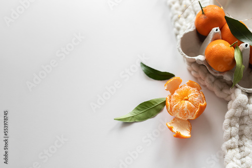 tangerines in an egg box and a white blanket on a white background. creative winter or new year layout. copy space. photo