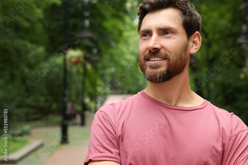 Portrait of handsome bearded man in park, space for text