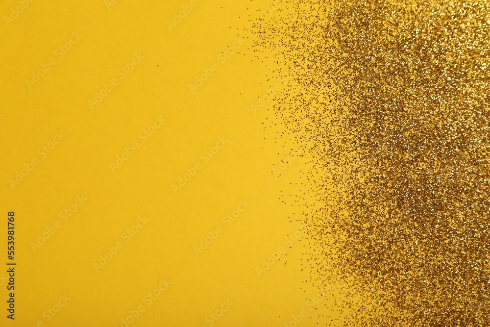 Shiny golden glitter on yellow background, top view. Space for text