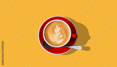 Aromatic coffee in red cup on yellow background, top view