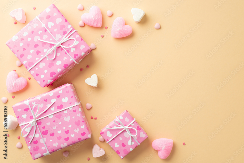 Valentine's Day concept. Top view photo of pink gift boxes heart shaped marshmallow candles and sprinkles on isolated beige background with empty space