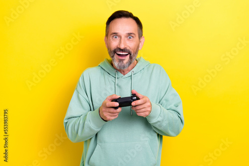 Photo of glad joyful man have free time enjoying playing favorite game home alone isolated on yellow color background © deagreez