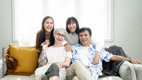 Happiness Asian family candid of daughter hugging the grandparent mother father senior elder cozy relax on sofa couch surprise visiting in living room at home, together hug cheerful Asian family home.